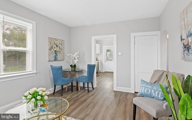 living area with wood finished floors, arched walkways, and baseboards