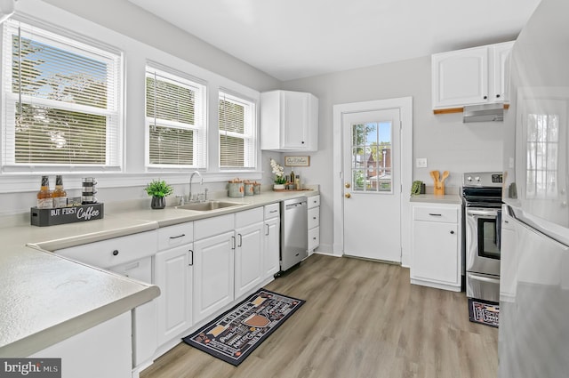 kitchen featuring a sink, stainless steel appliances, exhaust hood, and light wood-style flooring