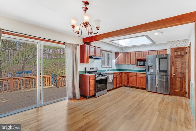 kitchen with under cabinet range hood, plenty of natural light, appliances with stainless steel finishes, and a skylight