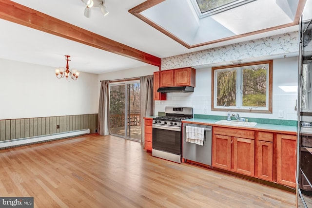 kitchen with beam ceiling, light wood-style flooring, a sink, stainless steel appliances, and under cabinet range hood