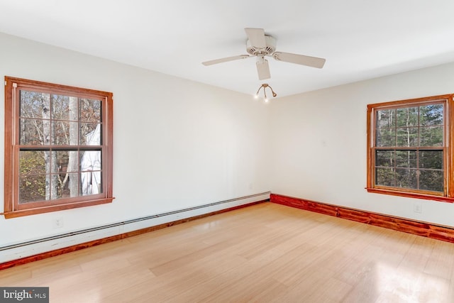 empty room with baseboard heating, a ceiling fan, baseboards, and wood finished floors