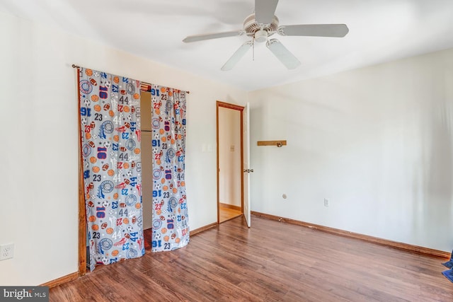 empty room featuring ceiling fan, baseboards, and wood finished floors