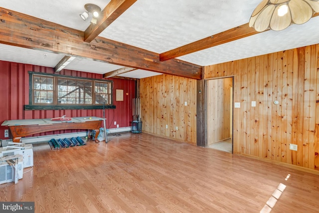 interior space featuring beamed ceiling, wood finished floors, wood walls, baseboards, and baseboard heating