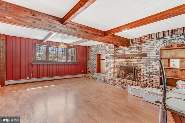 unfurnished living room with baseboard heating, beamed ceiling, a fireplace, and wood finished floors