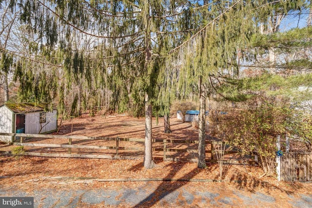 view of yard featuring an outbuilding, a storage shed, and fence