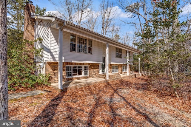 back of property with brick siding, a chimney, and a patio area