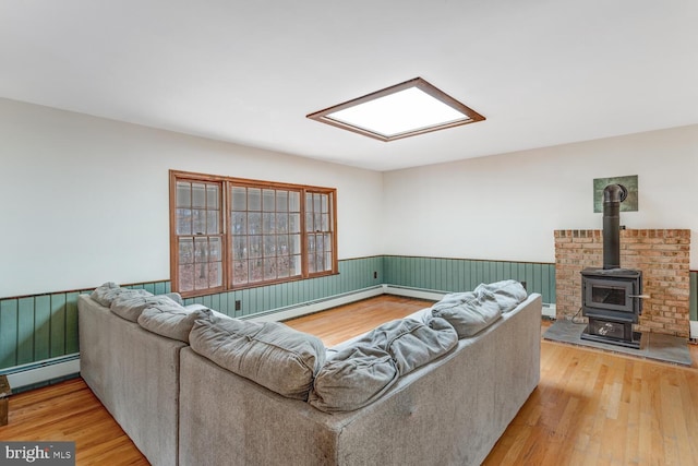 living area with a wainscoted wall, baseboard heating, light wood-type flooring, and a baseboard radiator