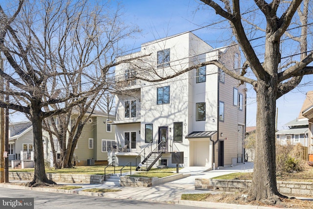 townhome / multi-family property featuring a balcony, cooling unit, a standing seam roof, a residential view, and metal roof