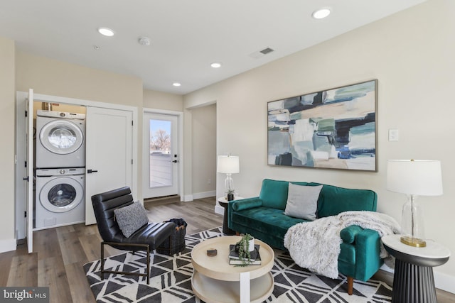 living area with visible vents, recessed lighting, stacked washer / drying machine, and wood finished floors