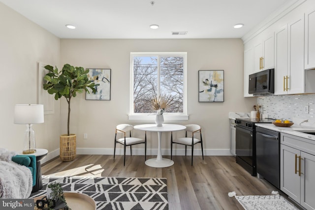 kitchen with backsplash, stainless steel dishwasher, wood finished floors, and light countertops