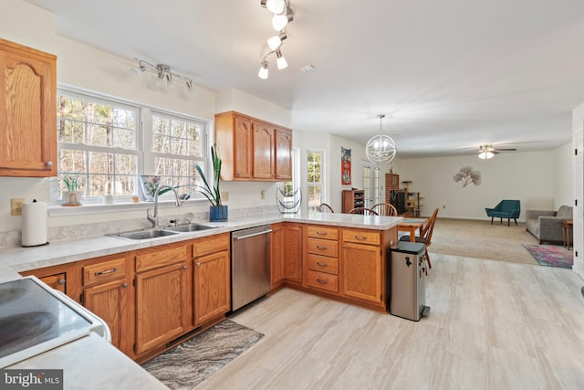 kitchen featuring a sink, open floor plan, a peninsula, light countertops, and dishwasher