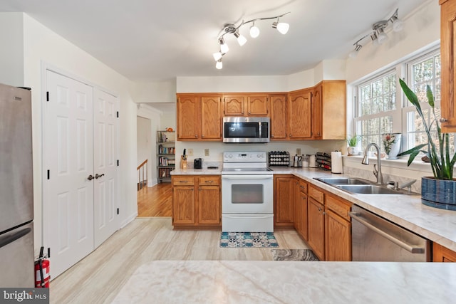 kitchen featuring brown cabinets, stainless steel appliances, light countertops, and a sink