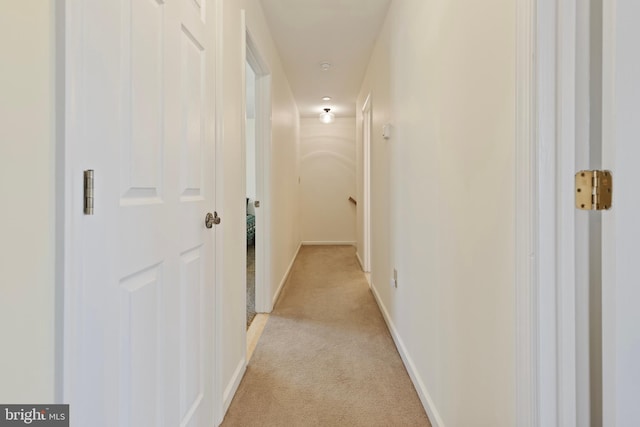 hallway with baseboards and light colored carpet