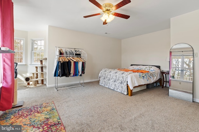 carpeted bedroom featuring baseboards, multiple windows, and a ceiling fan