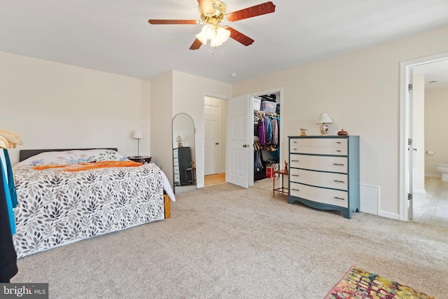 carpeted bedroom with baseboards, ceiling fan, a closet, a walk in closet, and connected bathroom