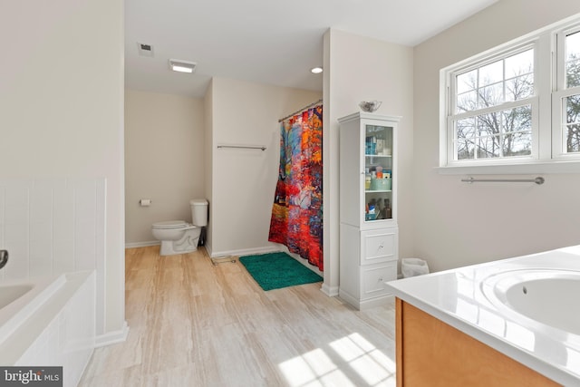 full bath with vanity, wood finished floors, visible vents, a tub, and toilet