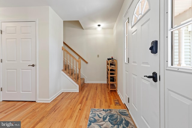 foyer entrance featuring stairway, baseboards, light wood-style floors, and visible vents