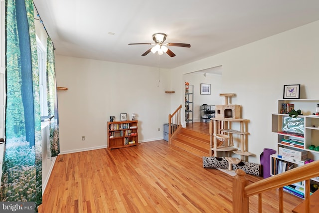 interior space with baseboards, stairs, a ceiling fan, and wood finished floors