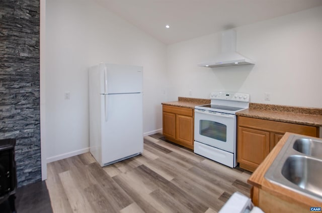 kitchen with lofted ceiling, light wood-style floors, white appliances, wall chimney exhaust hood, and a sink