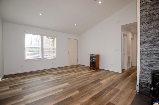 unfurnished living room with lofted ceiling, wood finished floors, and baseboards