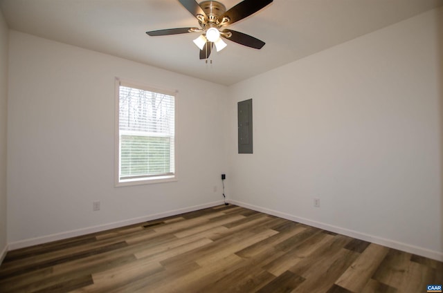 empty room with a ceiling fan, electric panel, wood finished floors, and baseboards