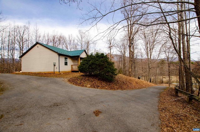 view of property exterior with metal roof and driveway