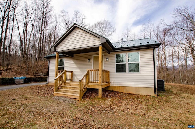 rear view of property featuring central AC unit and metal roof