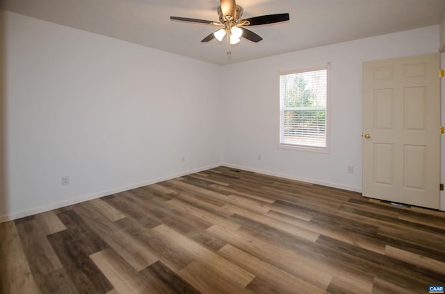 empty room featuring dark wood-type flooring, a ceiling fan, and baseboards