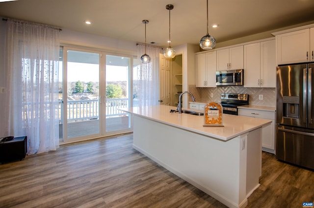 kitchen with dark wood-style floors, a sink, white cabinets, appliances with stainless steel finishes, and backsplash