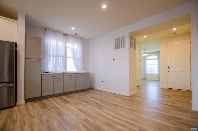 kitchen featuring light wood finished floors, visible vents, freestanding refrigerator, and gray cabinetry