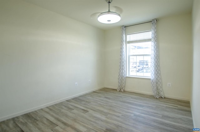 spare room featuring baseboards and wood finished floors