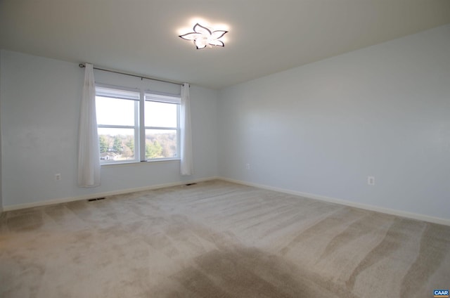 empty room featuring carpet flooring, baseboards, and visible vents