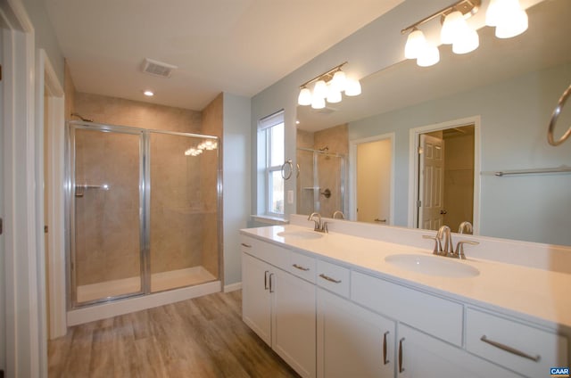 bathroom with a shower stall, wood finished floors, visible vents, and a sink