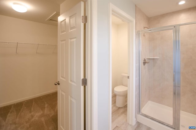 bathroom featuring baseboards, toilet, a spacious closet, and a shower stall