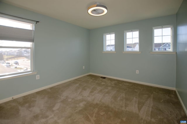 carpeted spare room featuring visible vents and baseboards