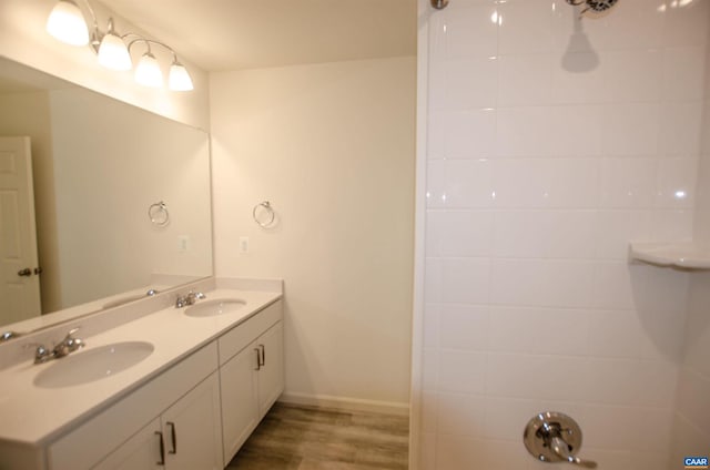 full bathroom with double vanity, wood finished floors, baseboards, and a sink