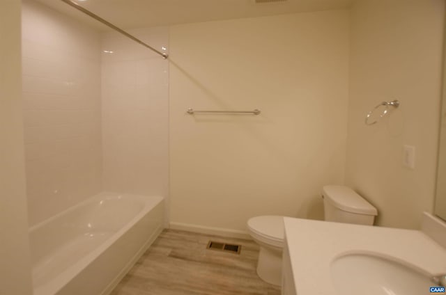 bathroom featuring vanity, wood finished floors, visible vents, bathing tub / shower combination, and toilet