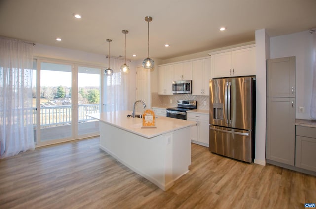 kitchen featuring light wood finished floors, tasteful backsplash, light countertops, stainless steel appliances, and a sink