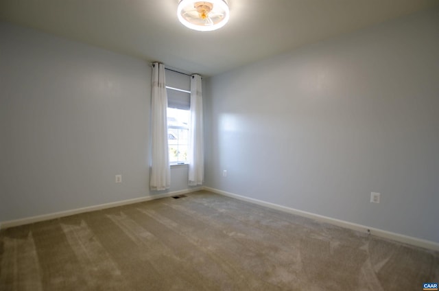 carpeted spare room with visible vents and baseboards