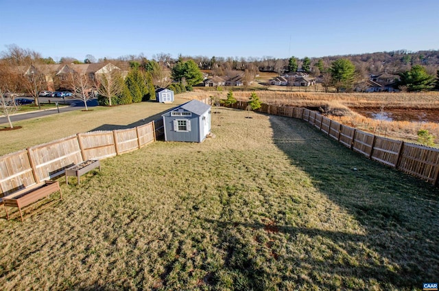 view of yard featuring a fenced backyard, a storage unit, and an outdoor structure