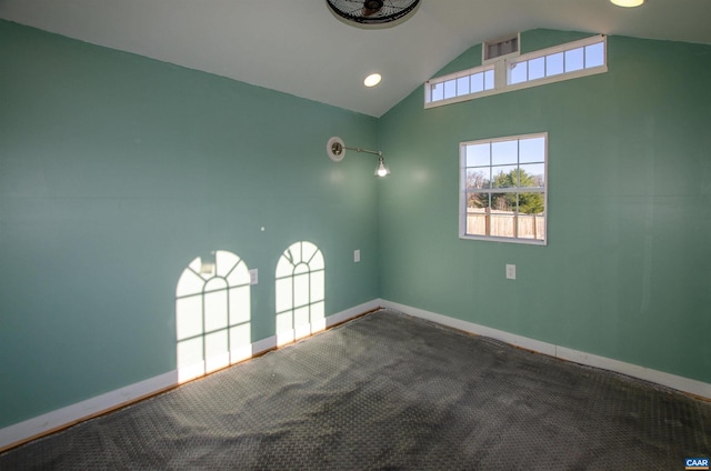 carpeted empty room with visible vents, baseboards, and vaulted ceiling