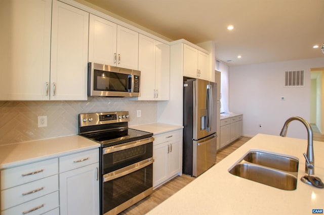 kitchen featuring visible vents, backsplash, light countertops, stainless steel appliances, and a sink