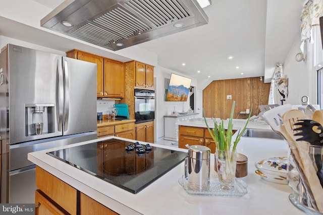 kitchen with brown cabinetry, black appliances, light countertops, and extractor fan