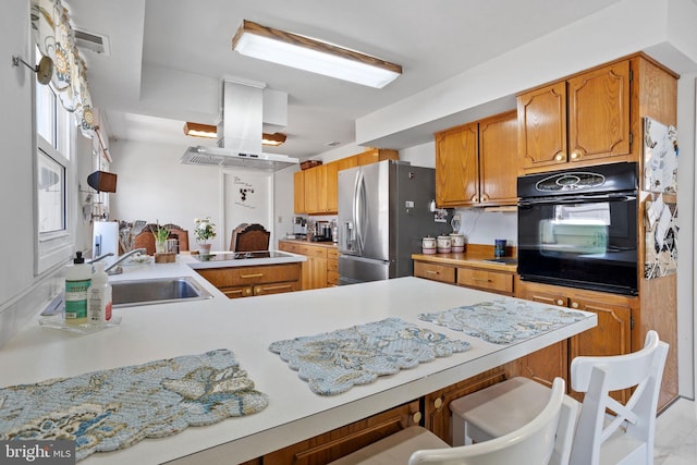 kitchen featuring a kitchen bar, island exhaust hood, black appliances, and light countertops