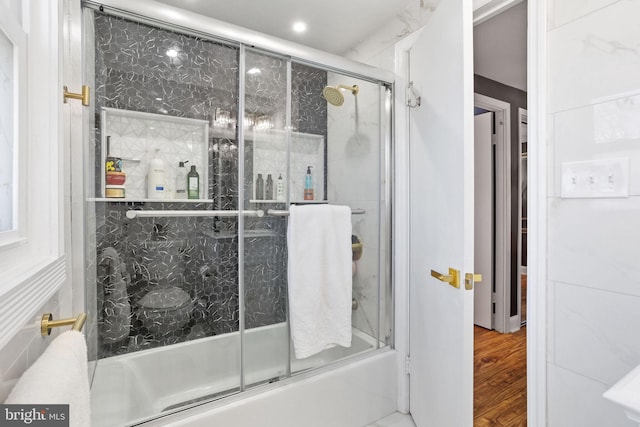 full bathroom with combined bath / shower with glass door and wood finished floors