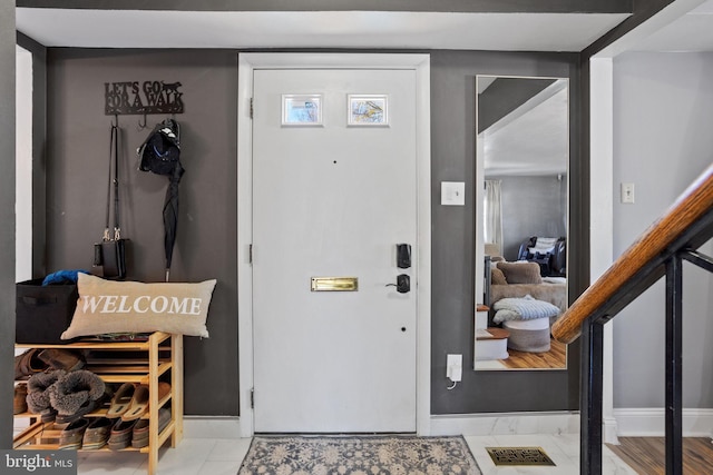 foyer with visible vents, baseboards, and stairway