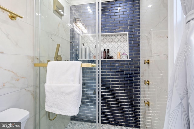 full bath featuring toilet, tiled shower, and tile walls