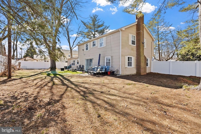 rear view of property featuring a chimney and fence