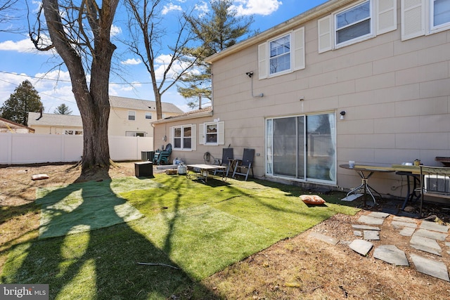 back of house featuring fence and a lawn