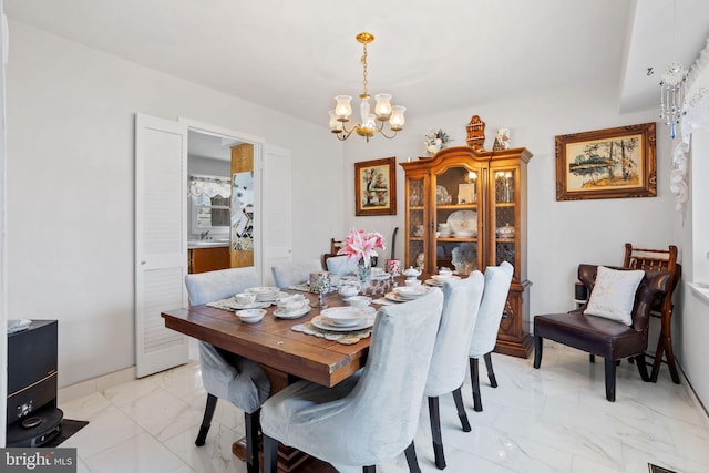 dining area featuring a notable chandelier, marble finish floor, and baseboards